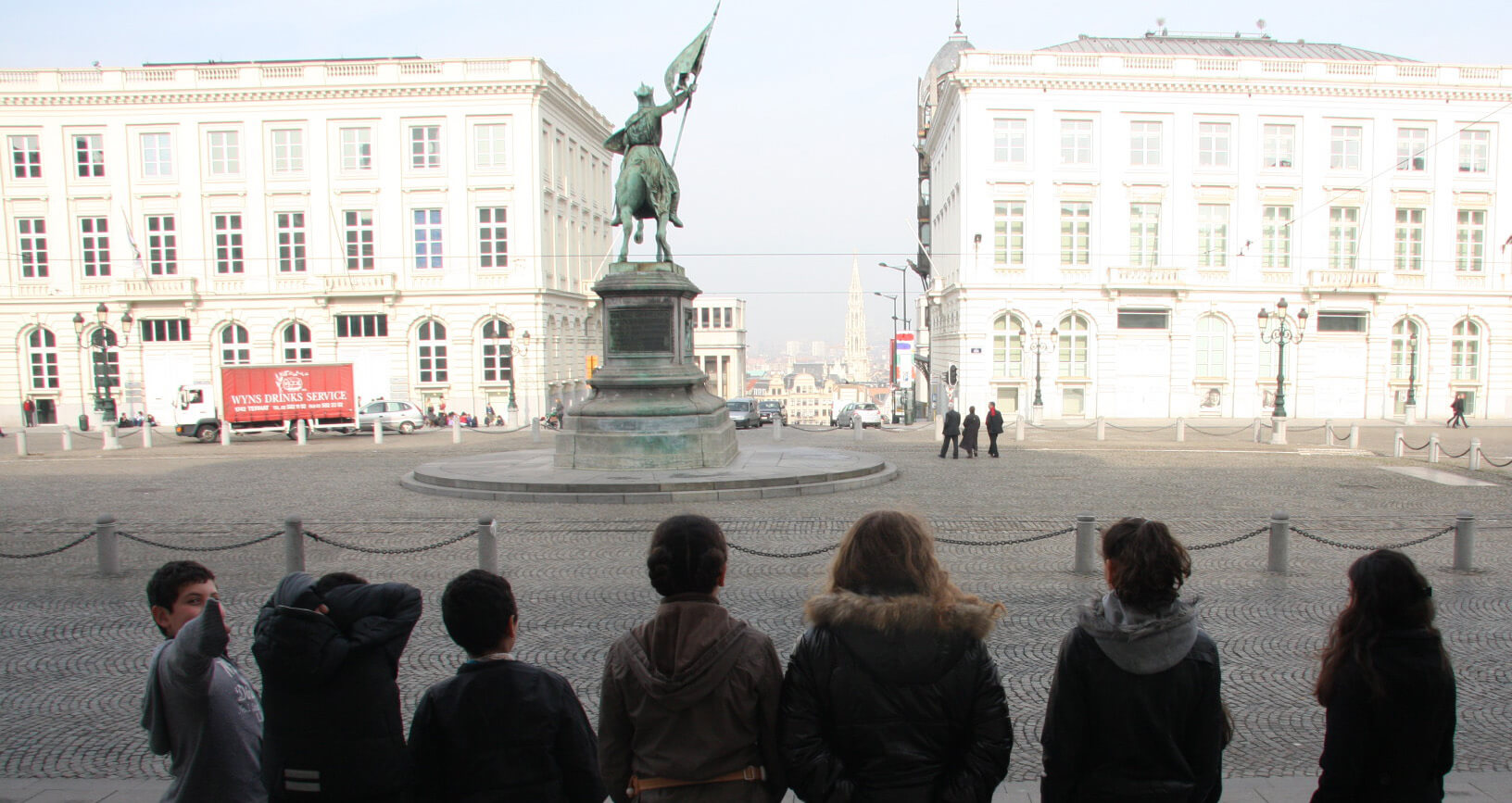 leerlingen kijken naar het standbeeld van Godfried van Bouillon op het Koningsplein richting Kunstberg